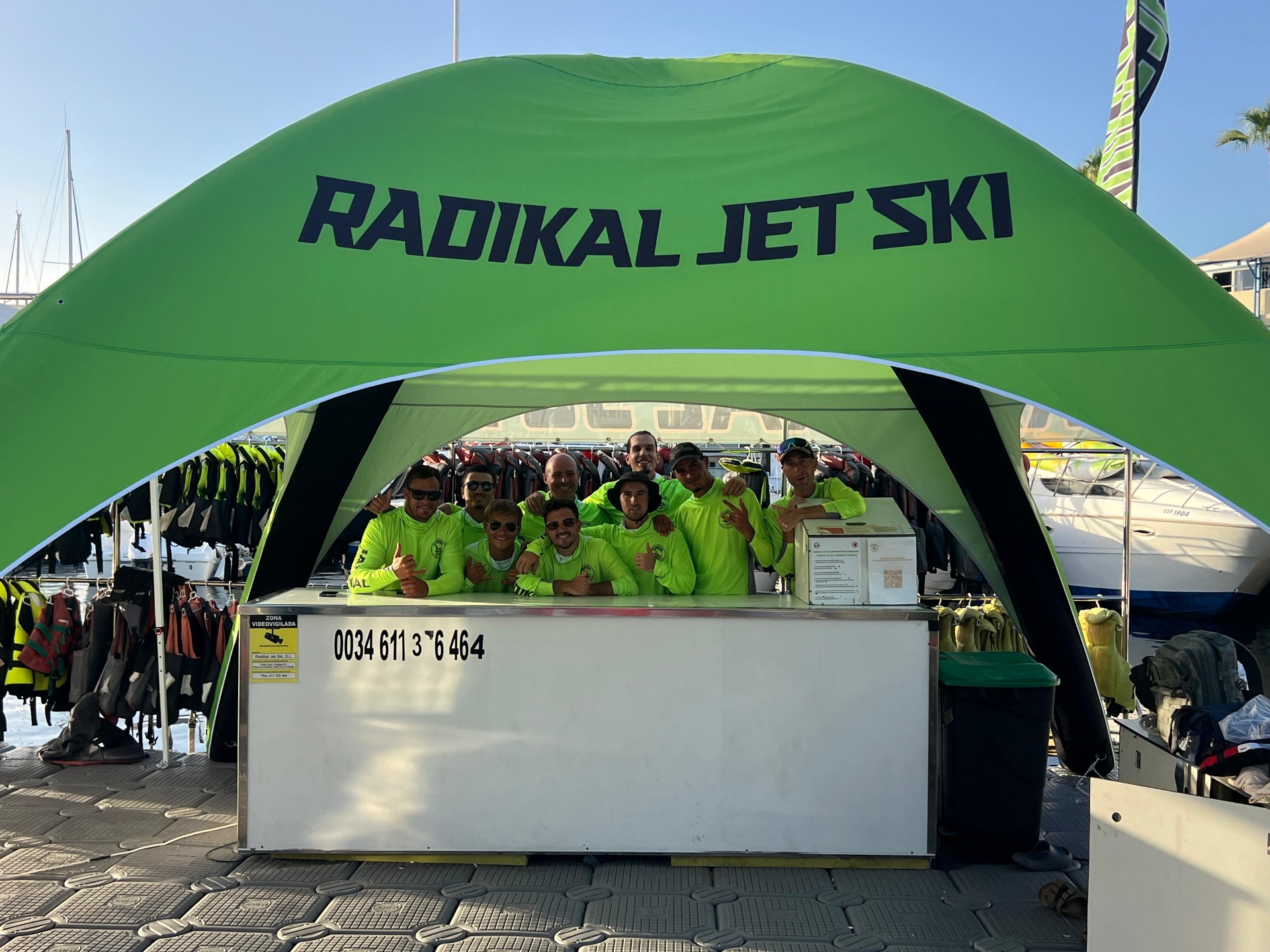 Equipo de monitores de Radikal Jet Ski bajo la carpa verde en Puerto Colón, Costa Adeje